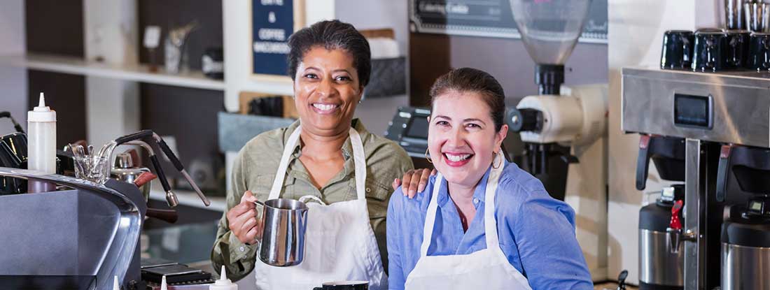 Two women wearing aprons behind a counter working in a coffee shop.  Find Phoenix, Arizona business insurance.