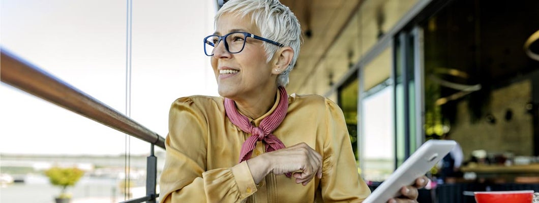 Senior woman wearing eyeglasses reading on digital tablet. Best Variable Annuities.