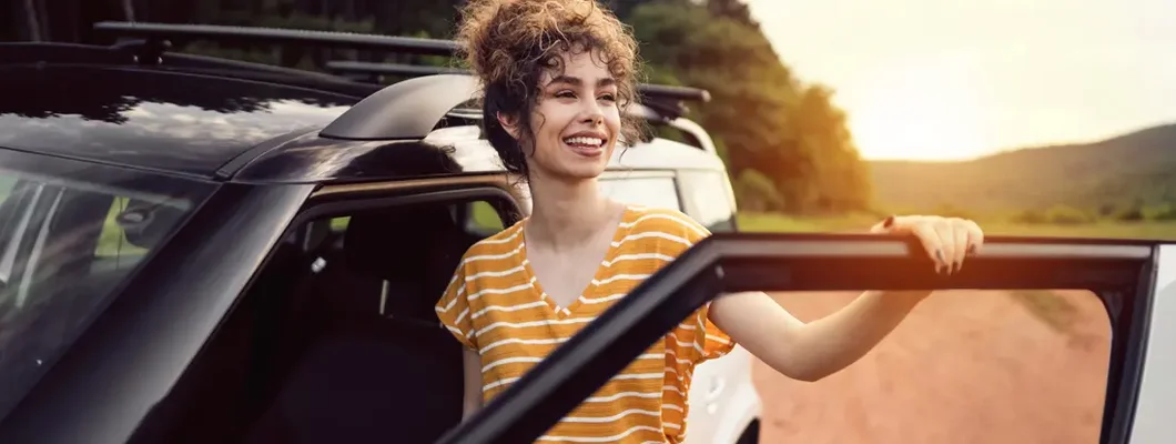 Woman standing by car and looking away. Find Huntsville, Alabama car insurance.