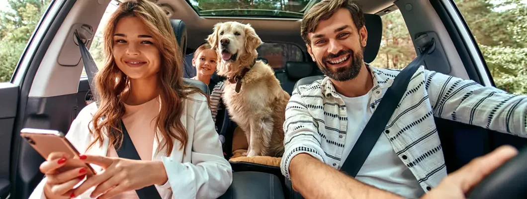 Family with dog in the car. The Dangers of Driving with Pets and How to Keep Them Safe. 