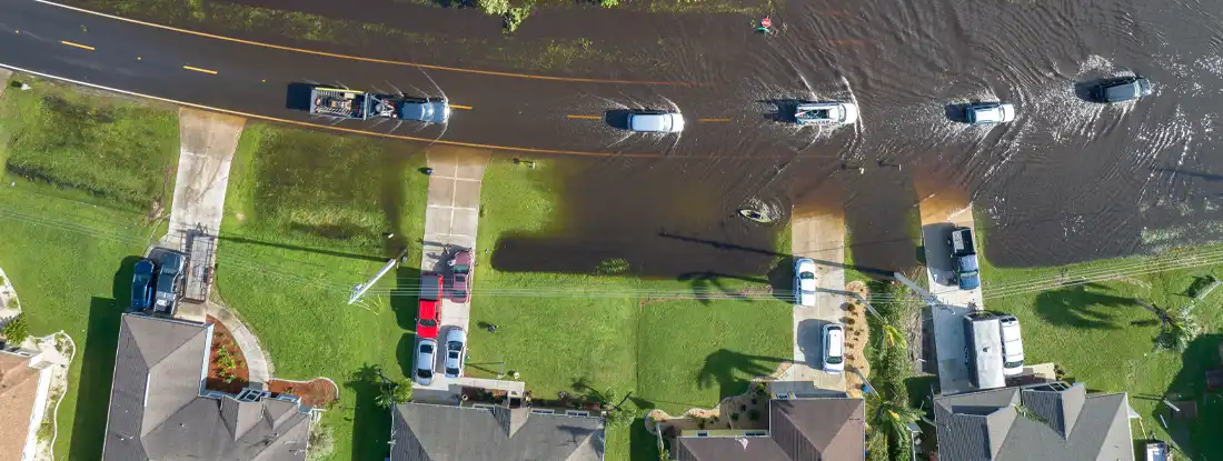 Aerial view of flooded street after hurricane rainfall with driving cars in Florida residential area. Buying a House in a Flood Zone.