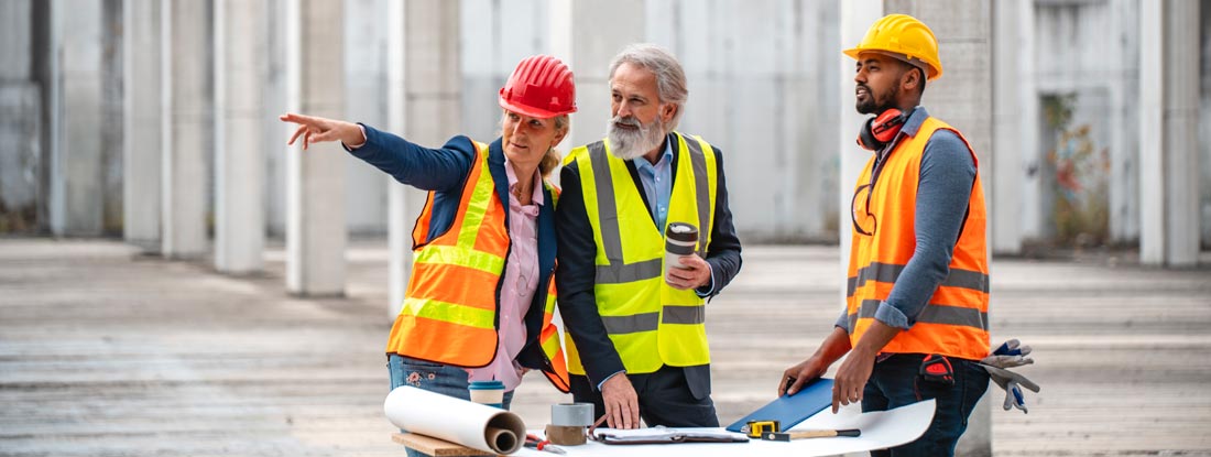 Professional construction project management team reviewing blueprints on a job site. Find Florida Builders Risk Insurance.