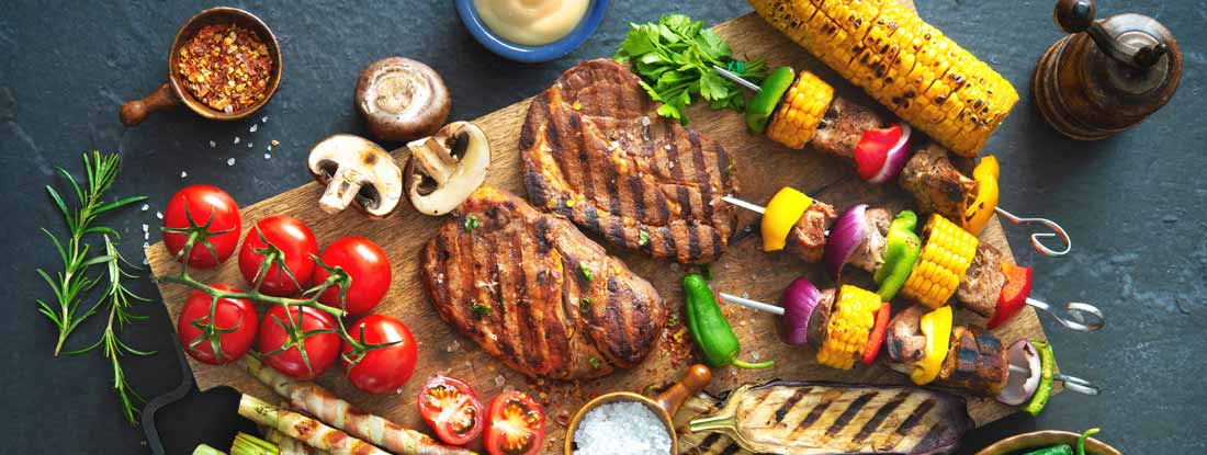 Barbecue menu. Grilled meat and vegetables on rustic stone plate. Find South Carolina Restaurant Insurance.