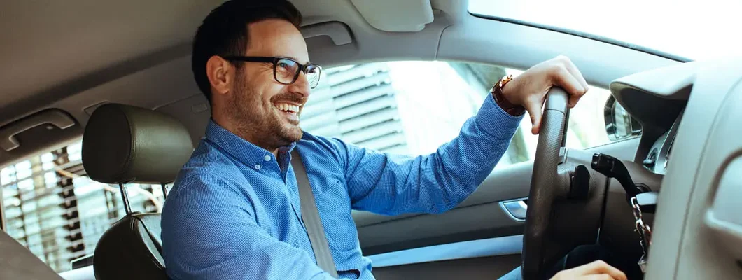 Handsome man driving car. Find Car Insurance Discounts.