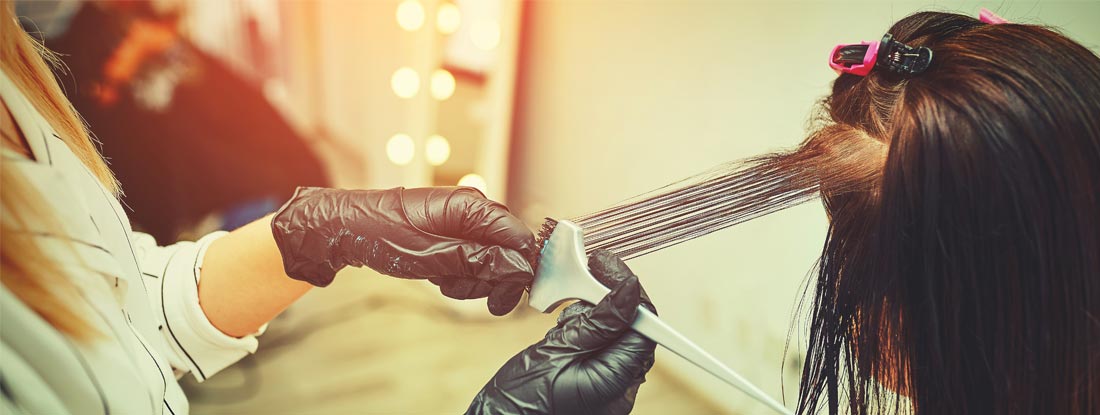 Woman gets new hair color at the salon from hairdresser. Find Hairdressers and Barbers Insurance.