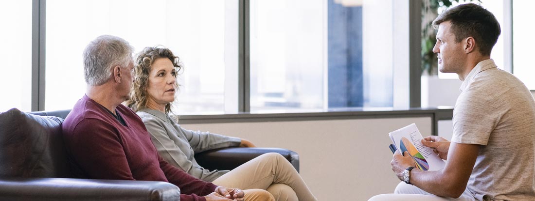 Financial planning meeting between a mature couple and a young financial advisor. Fixed annuities vs other investments.