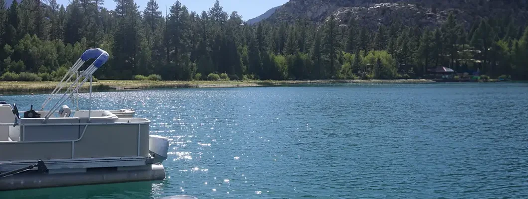 Pontoon boat docked along the shore on a sunny morning. Find Montana Boat Insurance. 