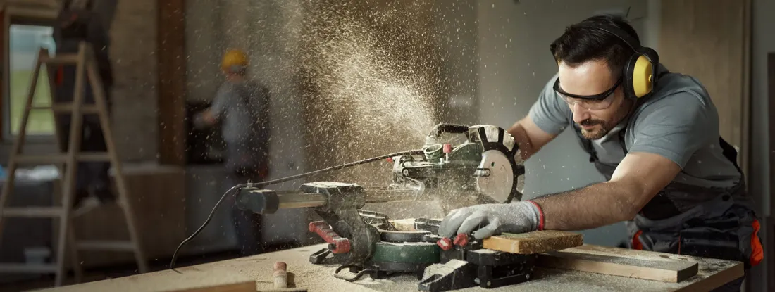 Carpenter cutting wood plank with electric saw at construction site. Find Business & Contractors Equipment Insurance.