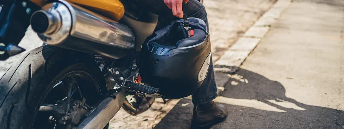 Biker man sitting on motorcycle, holding crash helmet. Find Mississippi Motorcycle Insurance.