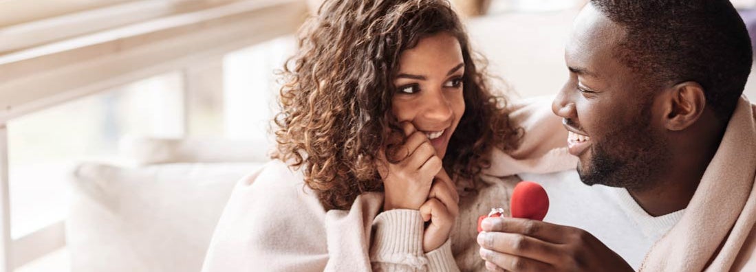 Cheerful man presents engagement ring to woman as they get engaged in the cafe