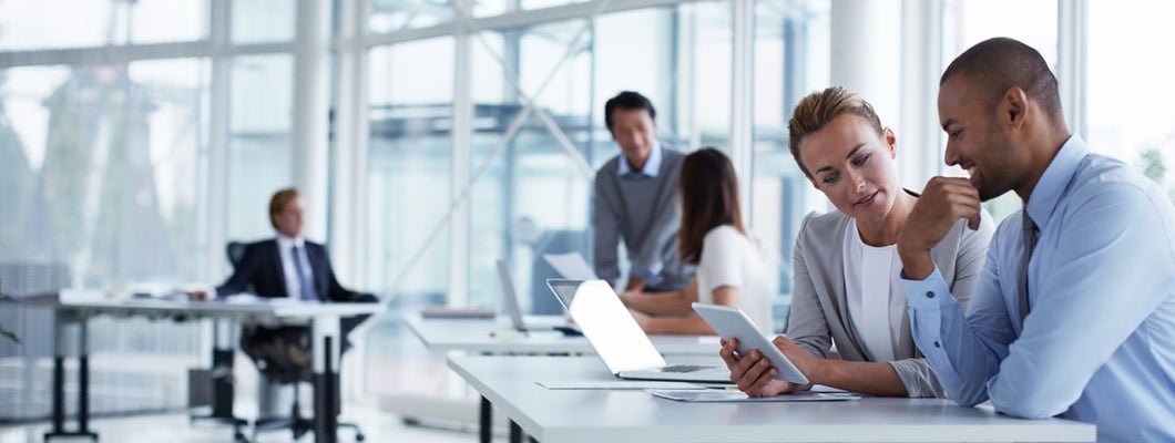 Business colleagues discussing over digital tablet at desk in corporate office
