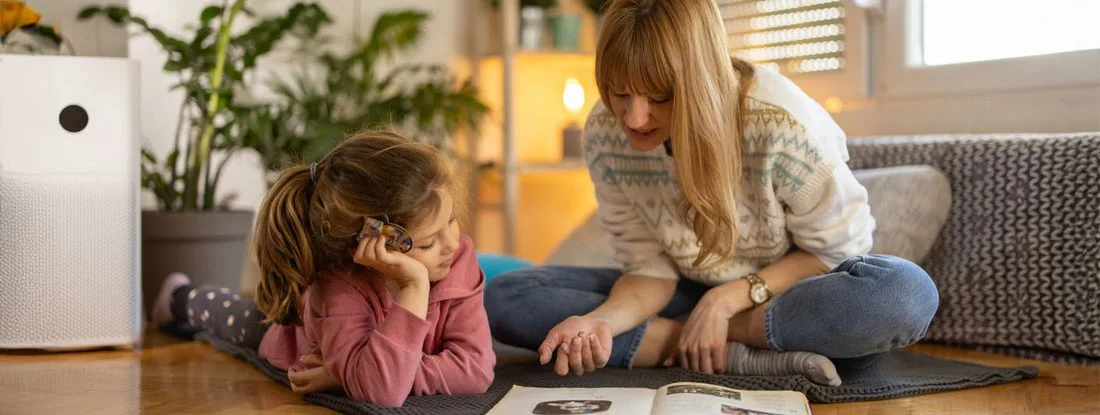 Mother and little daughter enjoying book together. Workers' Comp for Nanny.