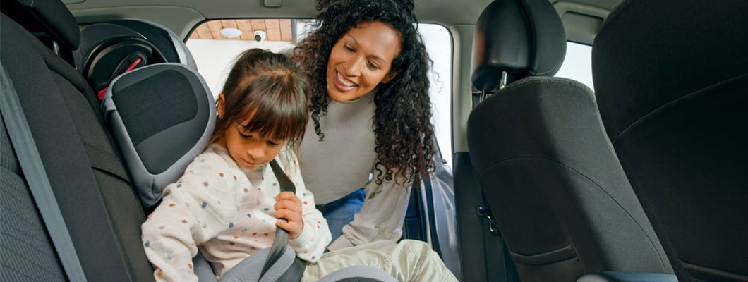 Mother helping daughter while fastening seat belt in car. How to Find the Best Car Insurance Coverage in West Fargo, North Dakota.
