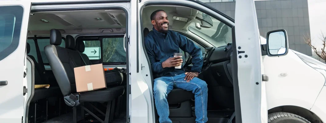 Cheerful Delivery Driver Taking a Break in Van. Find Maryland Commercial Vehicle Insurance.