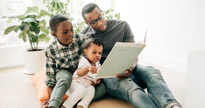 Dad reading a book for his kids at home. Compare Life Insurance Companies. 