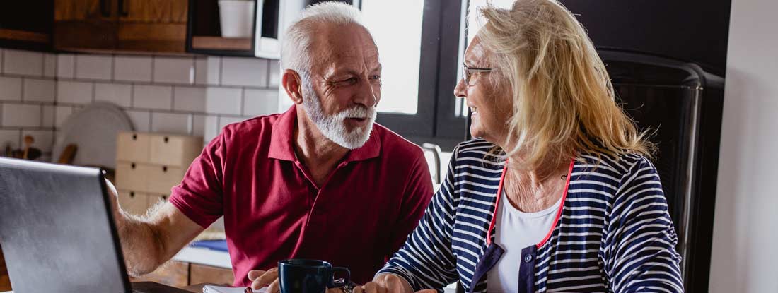 Couple discussing finances and using a laptop in a kitchen. Equity indexed annuity fixed or variable.