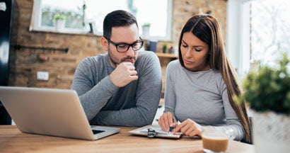 Couple reading and analyzing bills while sitting at table. What is a car insurance deductible?