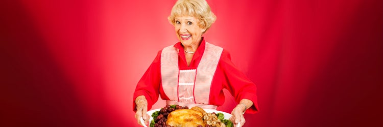 Sweet grandmother holding a beautifully cooked turkey dinner.