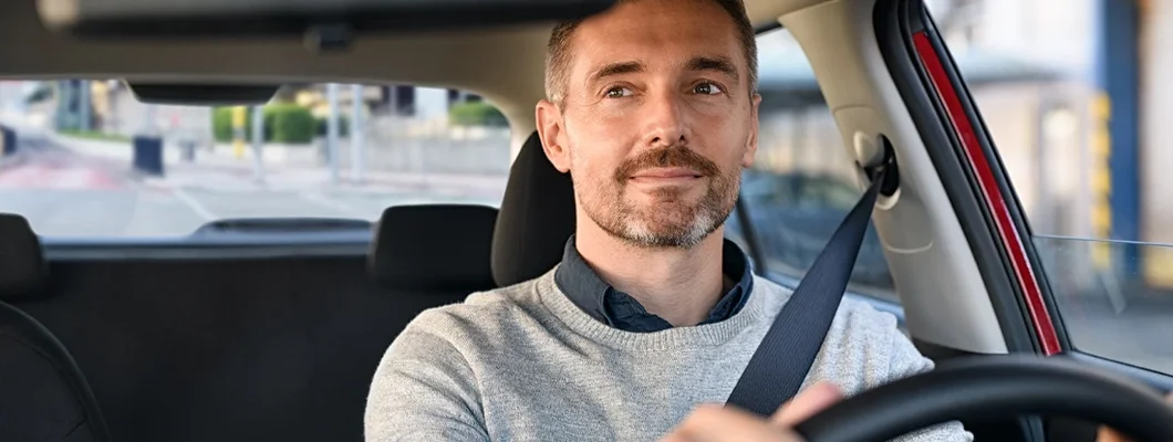 Man driving car and looking in mirror. York, Maine Car Insurance.