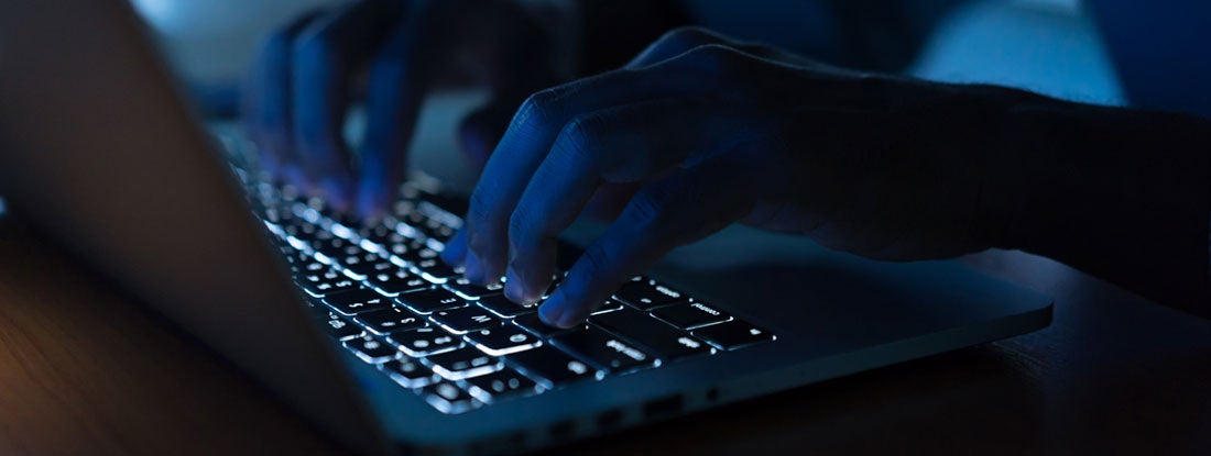 Programmer man hand typing on keyboard laptop. Commercial Crime Insurance.