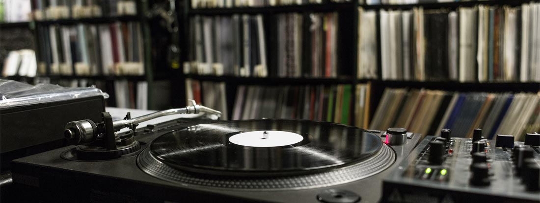 DJ Turntable Playing Vinyl at Record Store. Find Recording and Music Studio Insurance.