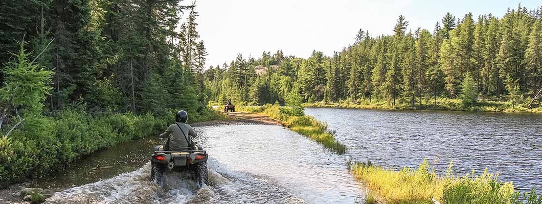 People driving ATV quads through water. Find ATV Insurance.