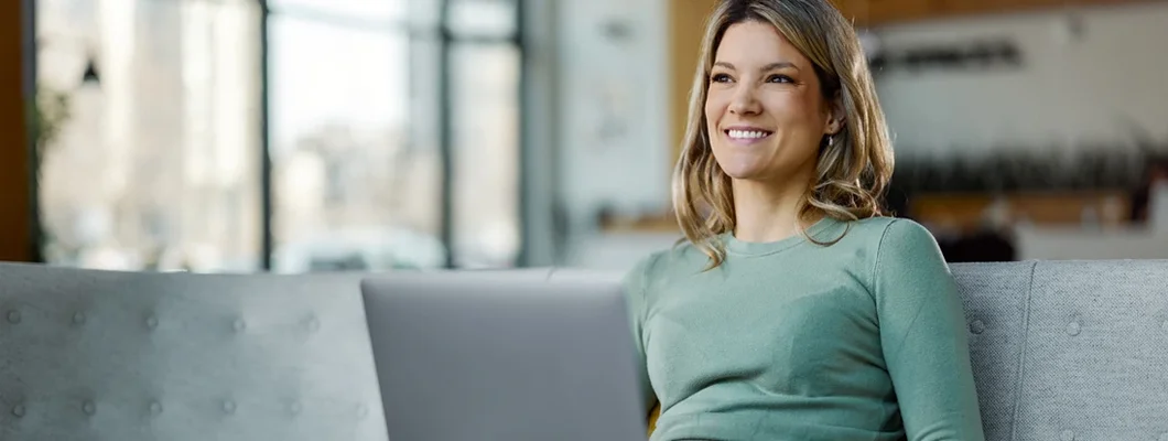 Woman using laptop on sofa in a hallway. 5 Pros and Cons of Buying a Car Online. 