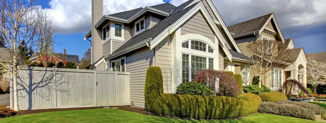 Classic American house with fence and green grass during spring. How to Find the Best Homeowners Insurance in Lewiston, Maine.