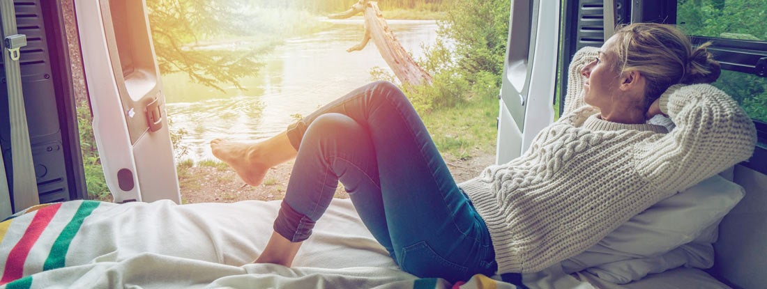 Young woman enjoying a stunning view out of the back of her RV. Find New Jersey RV Insurance.