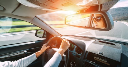 Woman driving car on highway. Find Good Driver Discounts.
