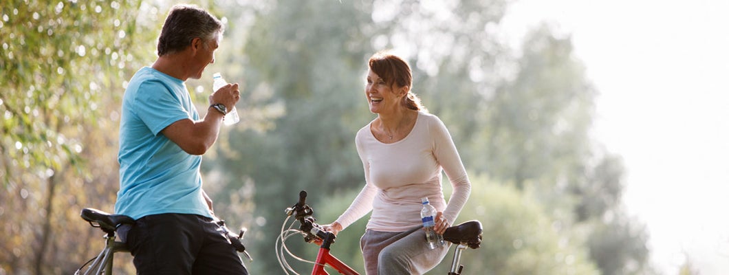 Couple with bicycles drinking water in city park. Find Philadelphia Pennsylvania life insurance.