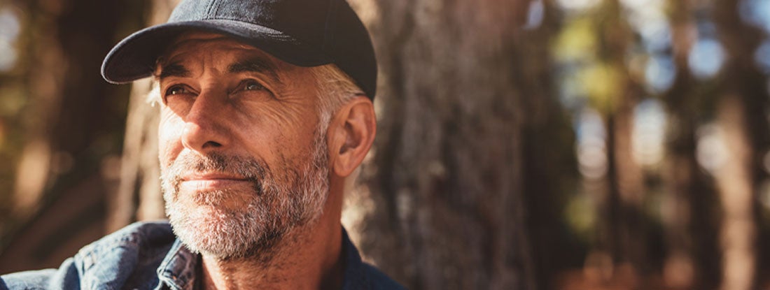Senior man sitting in woods on a summer day. No load variable annuity.