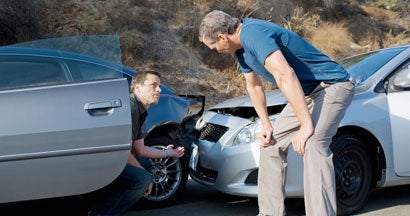 Two men examining damage in car collision. Who's responsible for damages if both drivers were at fault?