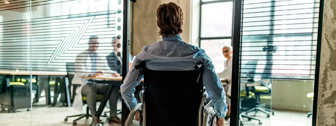 Rear view of a businessman in wheelchair entering the office. The Best Group Disability Insurance.