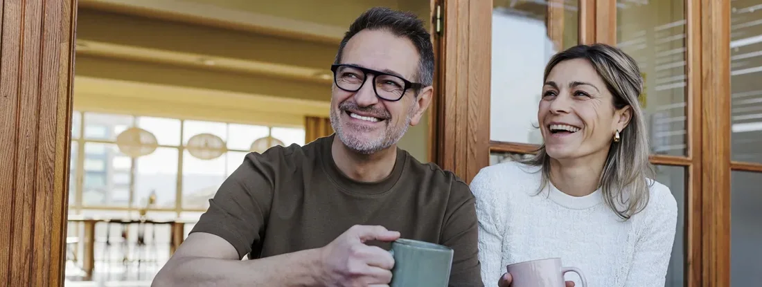 Couple enjoying coffee on a terrace at home. Find HMO Insurance.