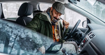 Mature man buckling her seatbelt in car. Is Warming Up Your Car Really Necessary?