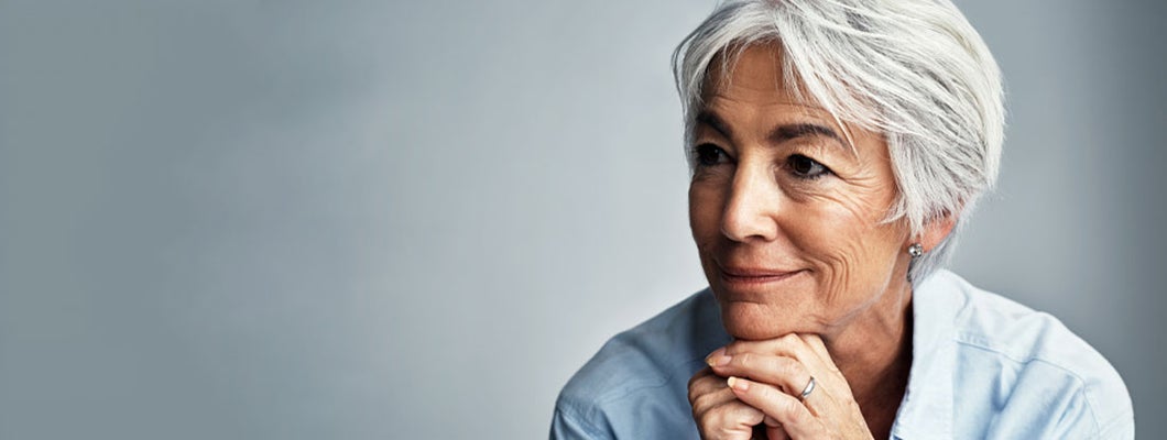 Senior woman looking thoughtful against a grey background. Are variable annuities qualified or unqualified.