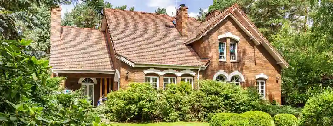 Backyard of a beautiful english style house with bushes and green lawn. Find HO8 Homeowners Policy Insurance.