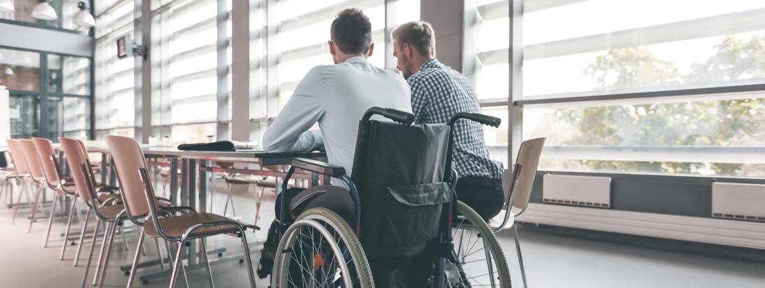 Disabled businessman working with his colleague in an office. What Is a Return to Work Program?