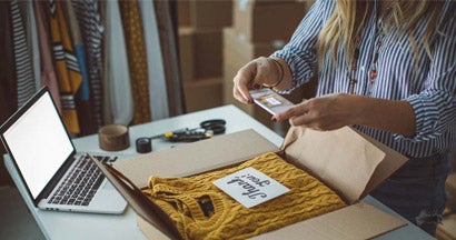 Small business owner packing product in boxes, preparing it for delivery.
