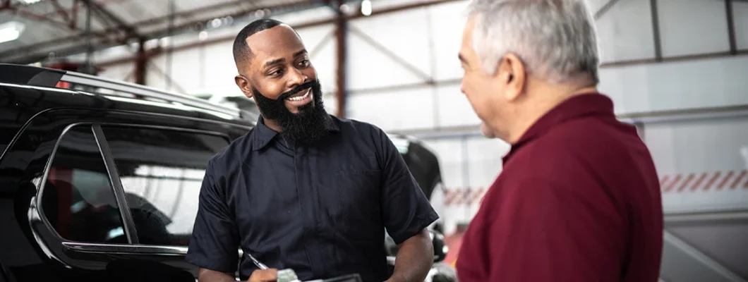 Mechanic man talking to his customer in auto repair. The Truth About Free Car Maintenance Programs.