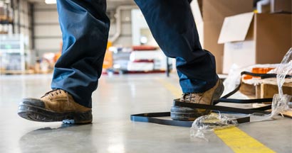A worker in danger of tripping over a piece of metal strapping in a factory.
