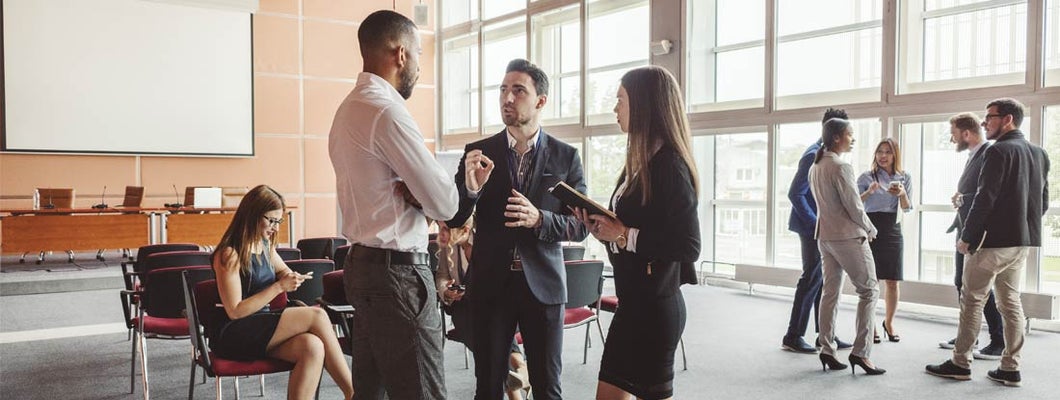 Business professionals networking and having discussions during what appears to be a conference or corporate event. Employee sponsored disability insurance.