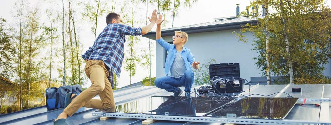 Father and Son Installing Solar Panels to a Metal Basis with a Drill. Eco friendly things you can do for your home.