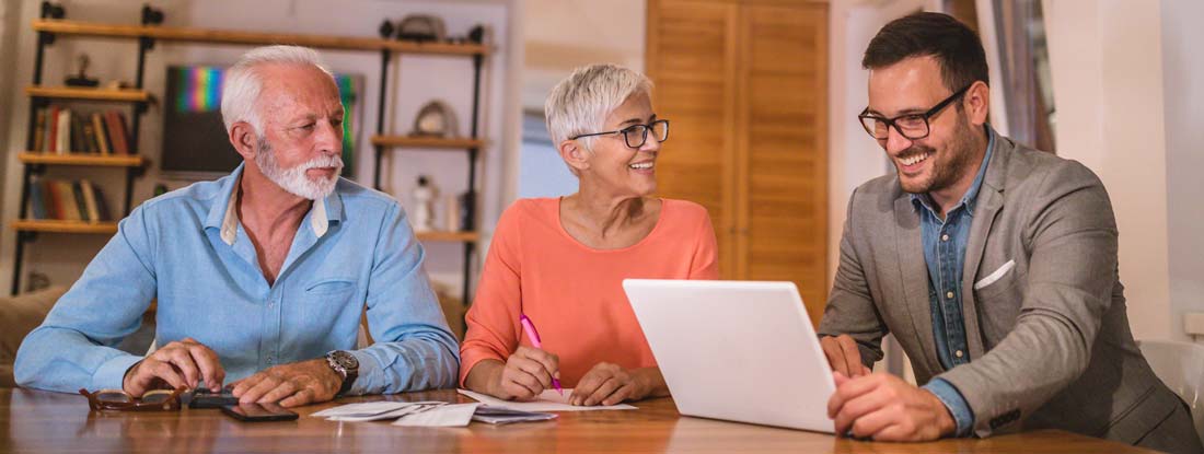 Financial advisor or insurance agent meeting with a senior couple in their home. Variable Annuities vs Fixed Index Annuities