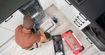 Technician Repairing Leaking Dishwasher. If My Dishwasher Leaks and Floods My Mississippi Home, Who Pays for the Damage?