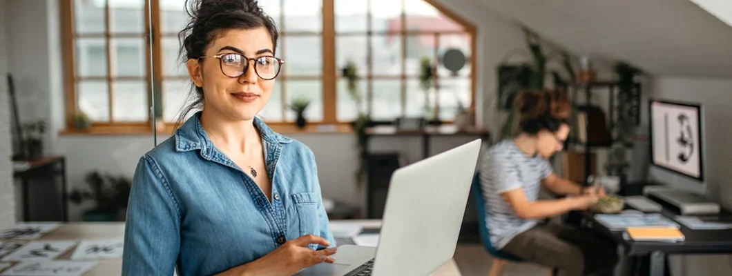 Office worker woman with laptop looking at camera. Business Insurance in Biddeford, Maine.
