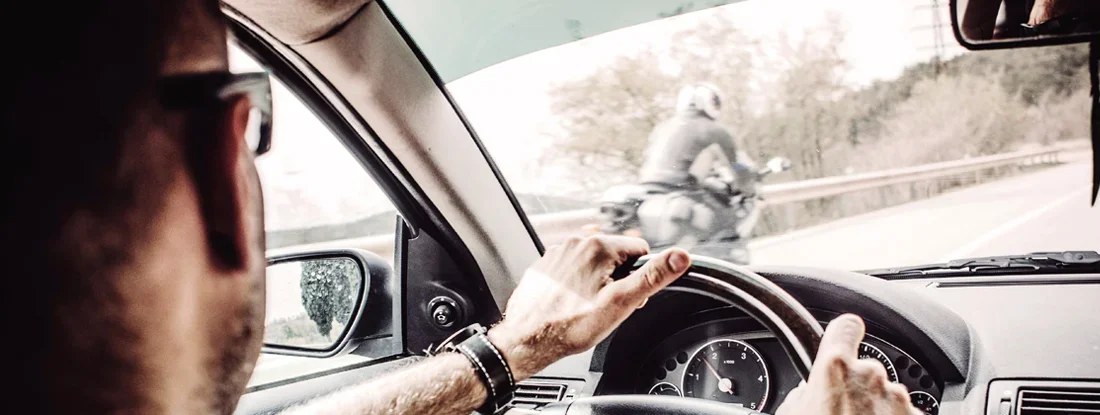 Man driving his Car with motorcycle overtaking. Motorcyclists: 8 Tips to Reduce Your Risk of Being Hit by a Car.