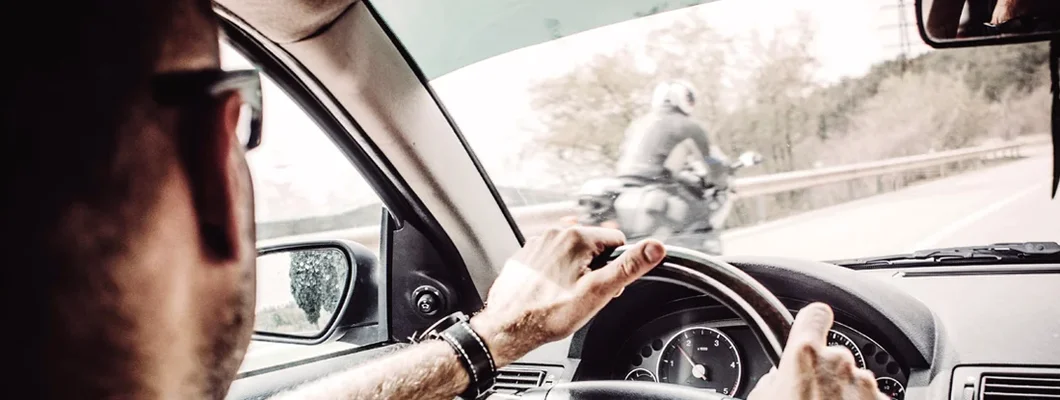 Man driving his Car with motorcycle overtaking. Motorcyclists: 8 Tips to Reduce Your Risk of Being Hit by a Car.