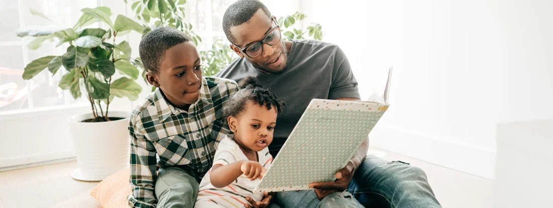 Dad reading a book for his kids at home. Compare Life Insurance Companies. 